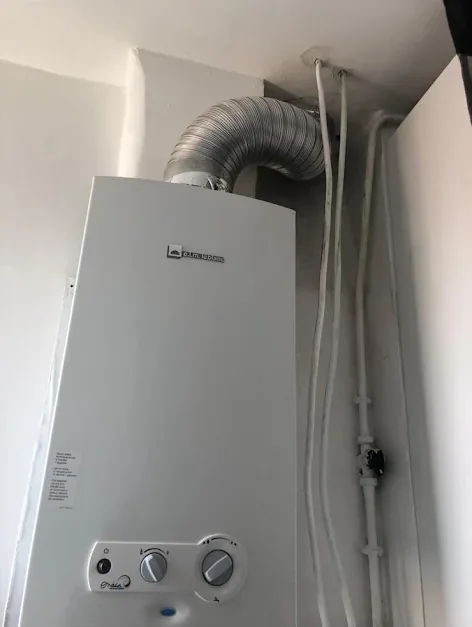 Chauffe-eau gaz mural avec conduit d'évacuation installé dans une cuisine